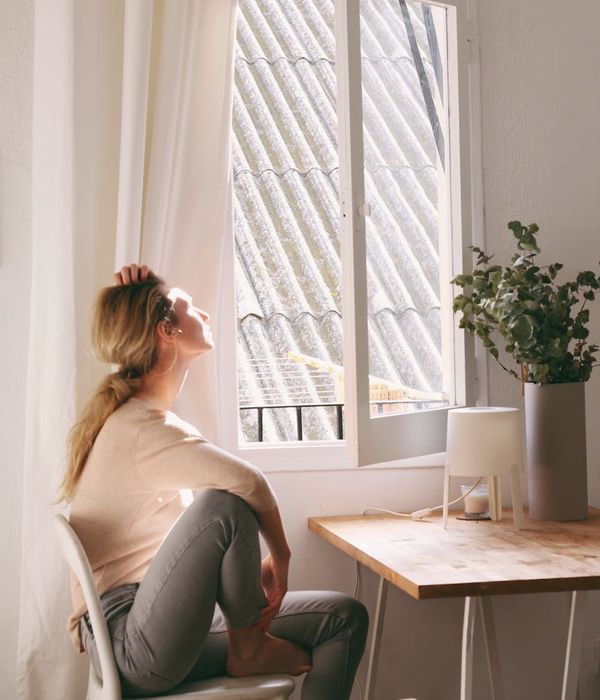Person sitting in a calm meditative pose in a brightly lit room.